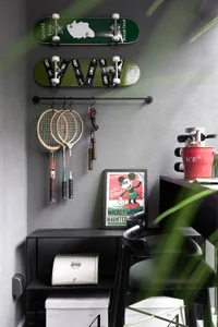 A home office with industrial design elements, including concrete walls, metal furniture, and skateboard decks hanging on the