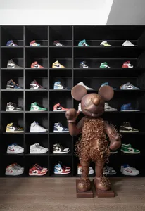 A metallic Mickey Mouse statue stands in front of a wall of shelves filled with various sneakers.