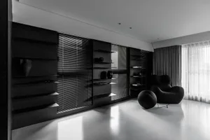 A minimalist residential interior featuring black metal furniture and glass elements.