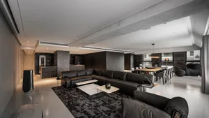 A modern living room featuring a black leather sofa set against a concrete backdrop.