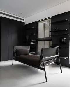 A minimalist bedroom with a black metal frame bed, black shelving, and a contrasting white floor.