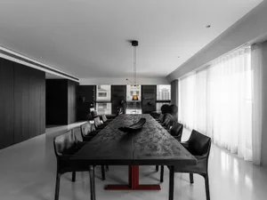 A modern black dining table with white curtains in a minimalist residential interior