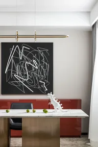 A modern dining area featuring a white marble table with green fruits, a white dinosaur figurine, and a black and white abstr