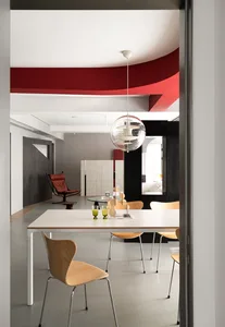 A modern dining room with a table, chairs, and a hanging light fixture.