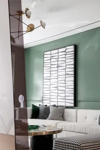 A modern living room with green walls, a white sofa, geometric wall art, and a round glass coffee table.