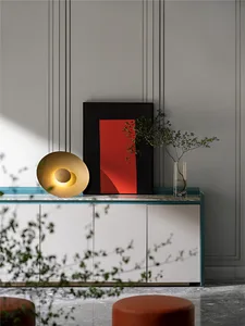 A modern living room featuring a metallic side table with a red geometric wall art and a plant.