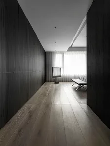 Modern minimalist bedroom with dark wooden walls, white curtains, and a sleek, contemporary bench and TV.