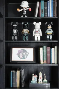 A modern black bookshelf displaying various books, toys, and figurines.