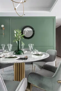 A modern dining room featuring a white marble table with green accents, surrounded by velvet upholstered chairs, and a geomet