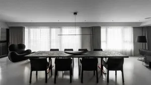 A sleek, minimalist modern dining room with a long black dining table and black chairs, featuring a long black horizontal lig