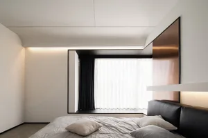 A minimalist bedroom with a metallic headboard, white curtains, and brown laminate flooring.