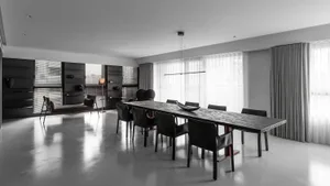 Modern minimalist dining room featuring a concrete table and black chairs.