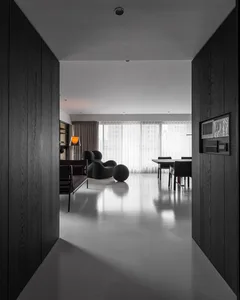 Contemporary living room with minimalist design, featuring a concrete floor, black furniture, and large windows with sheer cu