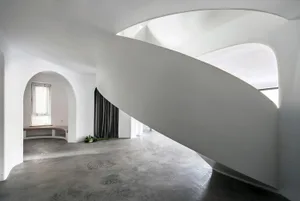 A modern, minimalist interior with concrete walls and spiral staircase.