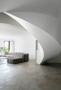 A modern living room with concrete walls and a large, open space.