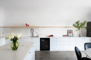 A modern minimalist kitchen featuring white marble countertops and white cabinets.