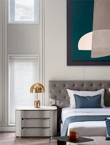 A modern bedroom with textured grey walls, white bedding, and a marble nightstand with a gold lamp.