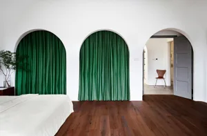Modern bedroom with green curtains and wooden floor.