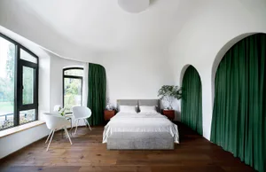 A modern bedroom with white furniture, green curtains, and a wood floor.