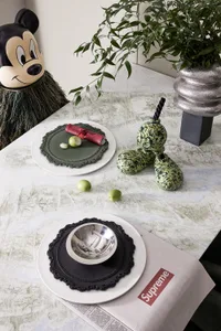 Modern dining room with marble surface, featuring green and black ceramic decorative items and a Mickey Mouse mascot.