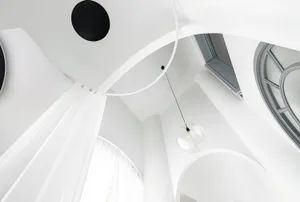 A modern white interior with glass and acrylic elements, featuring a circular light fixture and angular window.