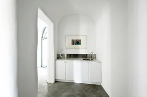 Modern minimalist kitchen with concrete countertops and white cabinetry.