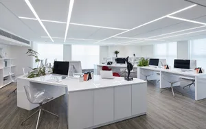 Modern minimalist office space with white furniture and glass windows.