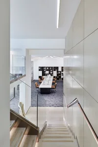 A modern office library space featuring neutral-colored walls and flooring with a minimalist design.