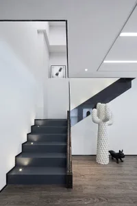 A modern staircase with black steps, concrete walls, and a black lantern style light fixture.