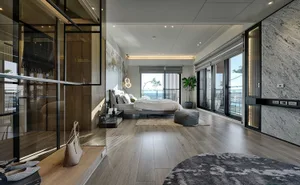 A modern bedroom with natural light from large windows, a wooden floor, and a comfortable bed.