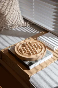 Modern coffee table with a wooden game board containing round wooden beads on a wooden tray.