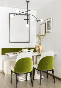 A modern dining room featuring a sleek table, white and green chairs, and minimalist decor.