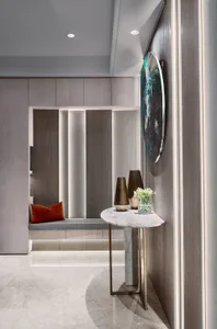 A modern entrance hall featuring marble flooring and wooden walls with a cushioned seating area and decorative elements.