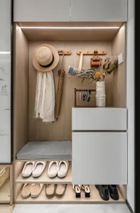 A modern entryway storage unit with a cushioned bench, shelves, and various items such as shoes, handbags, and decorations.