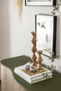 Modern interior design featuring minimalist wooden candlesticks on a green table.