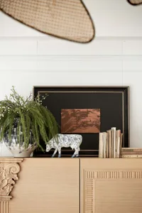 A modern interior space featuring a wooden cabinet topped with a plant, statue, books, and framed picture.