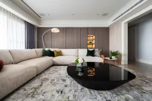 Modern interior design living room featuring a large beige sectional sofa with green and yellow throw pillows, a black coffee