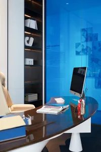 A modern office desk with a sleek, minimalist design featuring wood and glass materials.