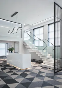 Modern office reception area with marble and glass staircase bordered by black metal railing.