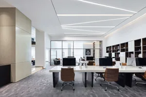 A modern office space featuring white interiors, glass walls, and wooden furniture.