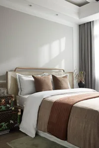 Minimalist bedroom with wooden bed frame, white bedding, and textured fabric accents.