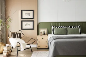 A modern bedroom with a green upholstered headboard, white bedding, and a cozy sitting area with a woven chair and sheepskin 