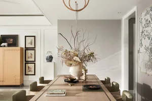 Modern dining room with a long table, chairs, and decorative items on the table.