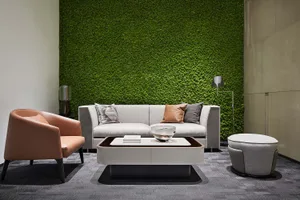 A modern living room with a green plant wall, white sofa, and coffee table with a bowl and book.