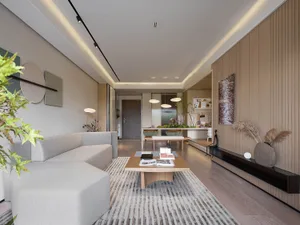 A modern residential living space with a comfortable sofa, a wooden coffee table, and a well-lit kitchen area with a wooden d
