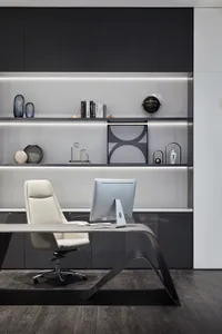 A modern office space featuring a sleek desk, white office chair, and a minimalist black and white color scheme with a glass 