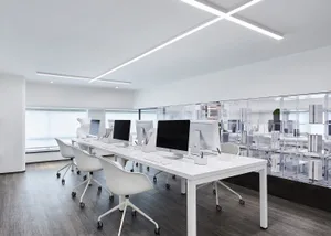 A modern office space with white desks and chairs, featuring minimalist design aesthetics and clear, efficient workspace layo