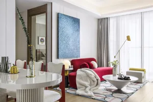 Modern living room featuring contemporary furniture, including a red sofa, white chairs, and a round table with a vase and pl