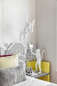 A modern bedroom featuring a unique light sculpture in the shape of a monkey holding a light bulb.