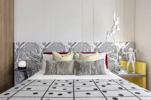 A modern bedroom interior featuring a patterned upholstered headboard and decorative pillows, with a 3D-rendered design.